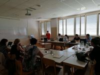 Photograph of 10 people sitting in a room listening to a woman presenter.