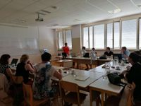 Photograph of 10 people sitting in a room listening to a woman presenter.