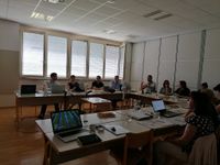 Photograph of 10 people sitting in a room listening to a woman presenter.