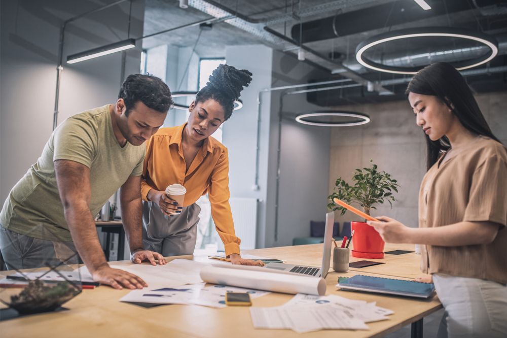 Three people standing around a table discussing a project in an industrial building